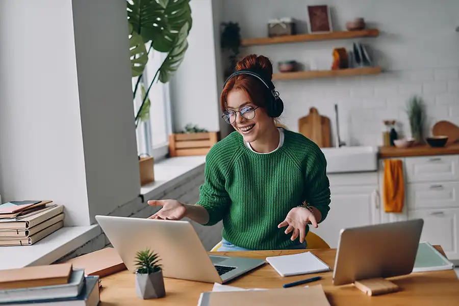 Person working from home, participating in a video call on her laptop in the kitchen.